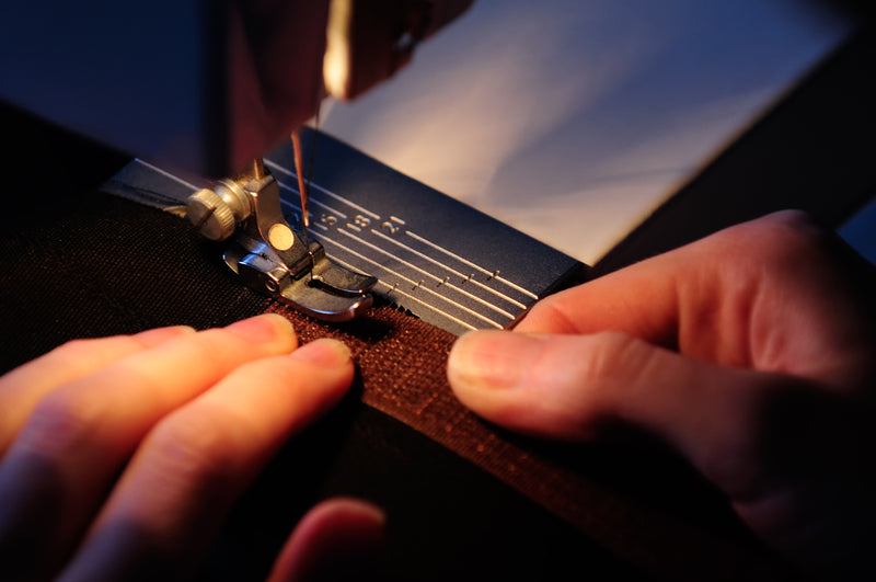 Close-up of hands sewing on a hook and loop strip with a sewing machine.