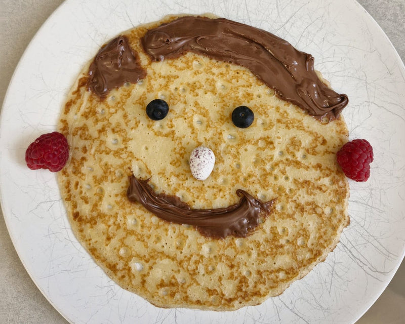pancake with a smile face made out of chocolate spread and fruit